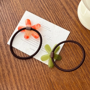 Pair of acetate flower hair ties in orange and green with elastic bands for women