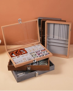 Detail of walnut wood jewelry box featuring clear glass lid and soft velvet compartments