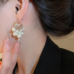Detail of silver C-shaped tassel earrings with clusters of pearls and sparkling crystals