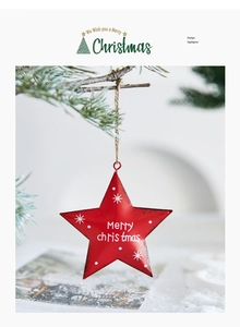 Red metal star ornament with Merry Christmas text hanging on a snowy pine branch