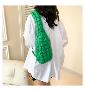 Gros plan sur un sac bandoulière vert en tissu texturé bulles sur l'épaule du modèle