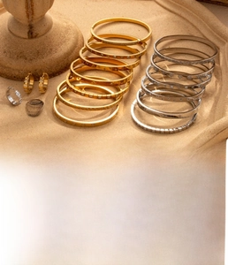 Detailed view of titanium steel bangles and earrings with zircons on a stone tray