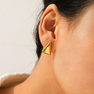 Close-up of model wearing geometric 18K gold-plated triangle stud earrings in stainless steel