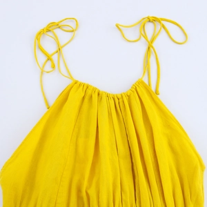 Detail of yellow backless dress showing cotton linen pleated texture and adjustable straps