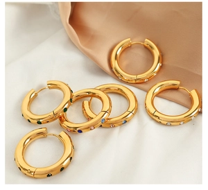 Détail de boucles d'oreilles créoles dorées à l'or 18K avec zircons colorés sur soie