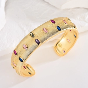 Detail of 18k gold plated cuff bracelet with multicolor oval gemstones and brushed finish