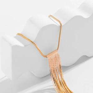 Detail einer minimalistischen Gold-Schlangenkette mit Steg und herabhängenden Quasten