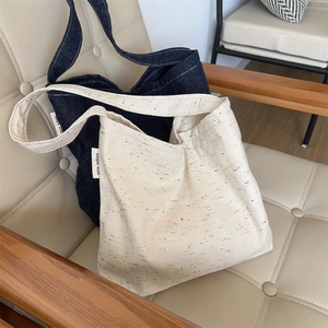 Dettaglio di borse tote in denim e tweed con etichetta simple wish sulla sedia