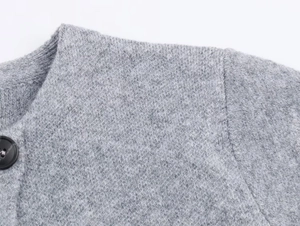 Détail du manteau en tricot gris montrant les coutures, l'encolure et le bouton noir