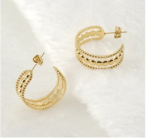 Détail de boucles d'oreilles en C plaqué or 18K avec texture perlée et lustre métallique