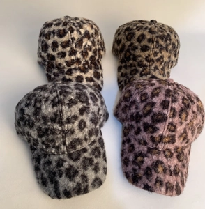 Detail view of four warm leopard print faux fur baseball caps in different trendy colors