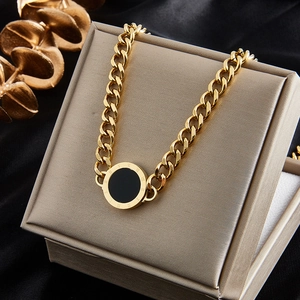 Close-up of gold Cuban chain bracelet with black circular Roman numeral pendant detail
