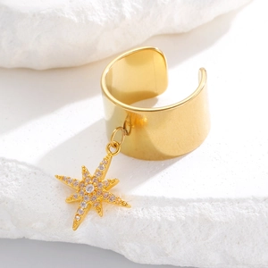 Λεπτομέρεια από χρυσό ear cuff με μενταγιόν αστέρι οκτώ ακτίνων και πέτρες ζιργκόν