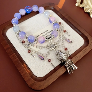 Detailed macro view of beaded flower bracelet with purple crystals and vintage metal tassel
