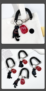 Detail of a black spring rope keychain with a cat pendant on a white canvas bag