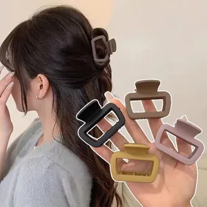 Matte rectangle hair claw clips in four colors shown on model and held in hand