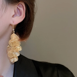 Close-up of gold layered petal tassel earrings worn by a model with elegant metallic shine