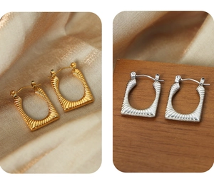 Macro detail of U-shaped gold and silver earrings with textured metallic finish