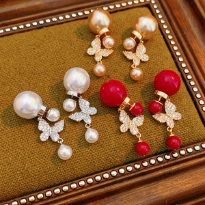 Detail of vintage gold plated butterfly pearl earrings in white, champagne, and red sets
