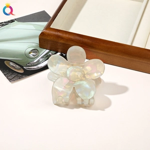 Detailed view of a white pearlescent flower hair claw clip with a glossy resin finish