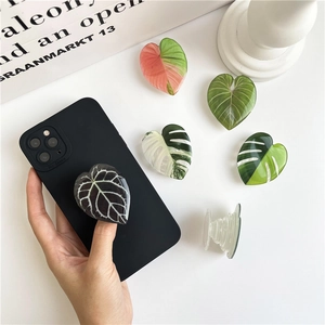 Macro shot of green monstera leaf pattern on adjustable phone grip for desktop