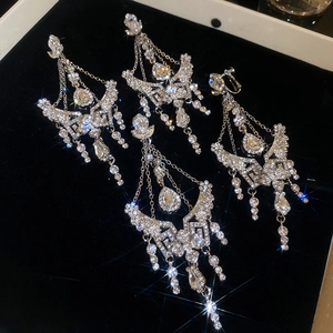 Detail of silver drop earrings with shimmering crystals and tassels on black velvet background