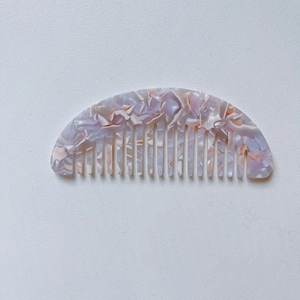 Macro detail of half-round hair comb with pink purple marble texture in cellulose acetate