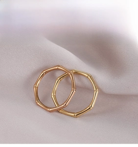 Detailed view of bamboo-shaped gold and rose gold rings on soft beige silk fabric