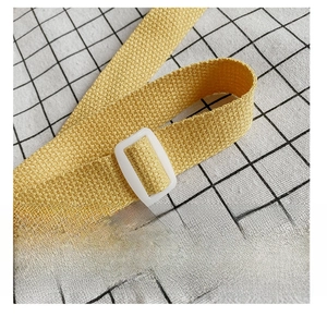 Detail of adjustable yellow woven shoulder strap with white plastic buckle on bag