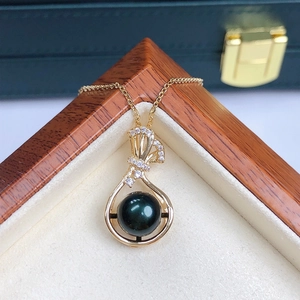 Detailed macro view of a black pearl pendant on a gold chain with ribbon-shaped crystals