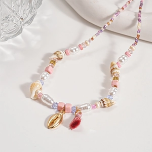Detail of beaded necklace with sea shells, pearls, and pink tassels on a white surface