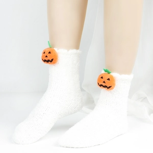 Nahaufnahme weißer Plüschsocken aus Korallenvlies mit niedlicher Kürbis-Dekoration