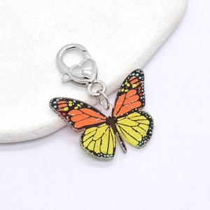 Detail of vibrant orange butterfly keychain with acrylic wings and heart-shaped silver clasp