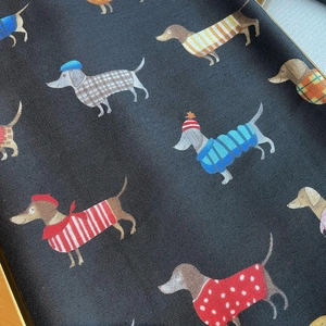 Detailed close-up of woven cotton-linen fabric with colorful dachshund dog illustrations