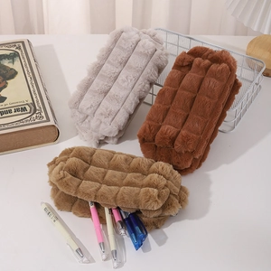 Three plush plaid pencil cases in earthy tones displayed on a minimalist desk setup