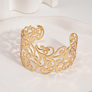 Vista dettagliata del bracciale rigido dorato traforato con motivi floreali