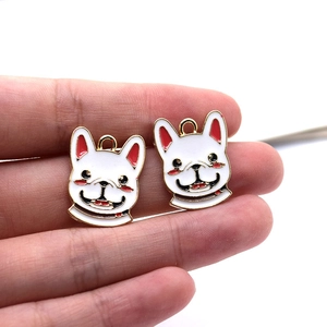 Macro view of white enamel French Bulldog charms held between fingers for size reference