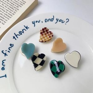 Set of 6 mini heart acetate hair claws in solid colors and checkerboard patterns on a plate