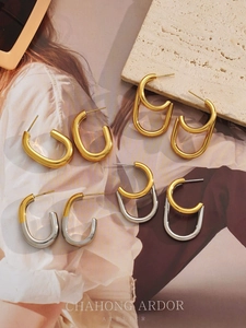 Macro detail of 18k gold plated C-shaped geometric earrings on a luxury stone surface