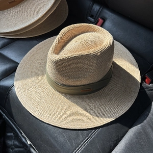 Detail of handmade raffia sun hat with green ribbon and leather handmade tag