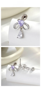 Détail macro de boucles d'oreilles nœud en argent avec zircon cœur mauve et pendentif