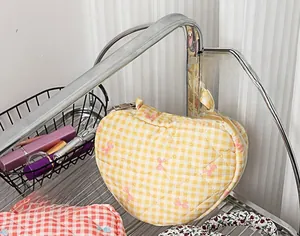 Quilted heart-shaped cosmetic bags with floral bows on a modern storage shelf