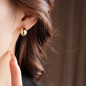 Close-up of minimalist gold plated stud earring worn by a model in a lifestyle setting