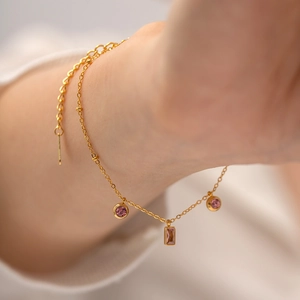 Bracelet plaqué or 18 carats avec pendentifs en zircon rose porté au poignet d'un modèle