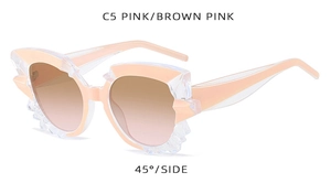Detail view of pink irregular cat-eye sunglasses with crystal-cut textured frames
