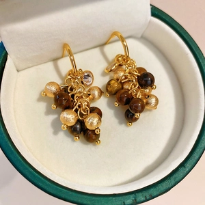 Detail of golden cluster earrings with brown beads in a green jewelry box