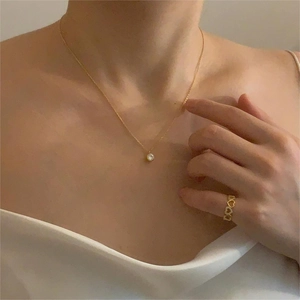 Detailed view of a gold cubic zirconia pendant necklace and hollow heart-shaped rings