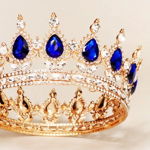 Detailed view of luxury gold bridal crown featuring large blue teardrop gems and crystals