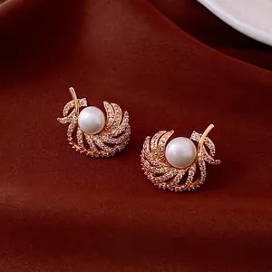 18k gold plated feather pearl stud earrings with sparkling cubic zirconia on velvet