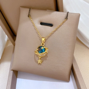 Close-up of a golden planet pendant with blue galaxy motif and star on a jewelry box